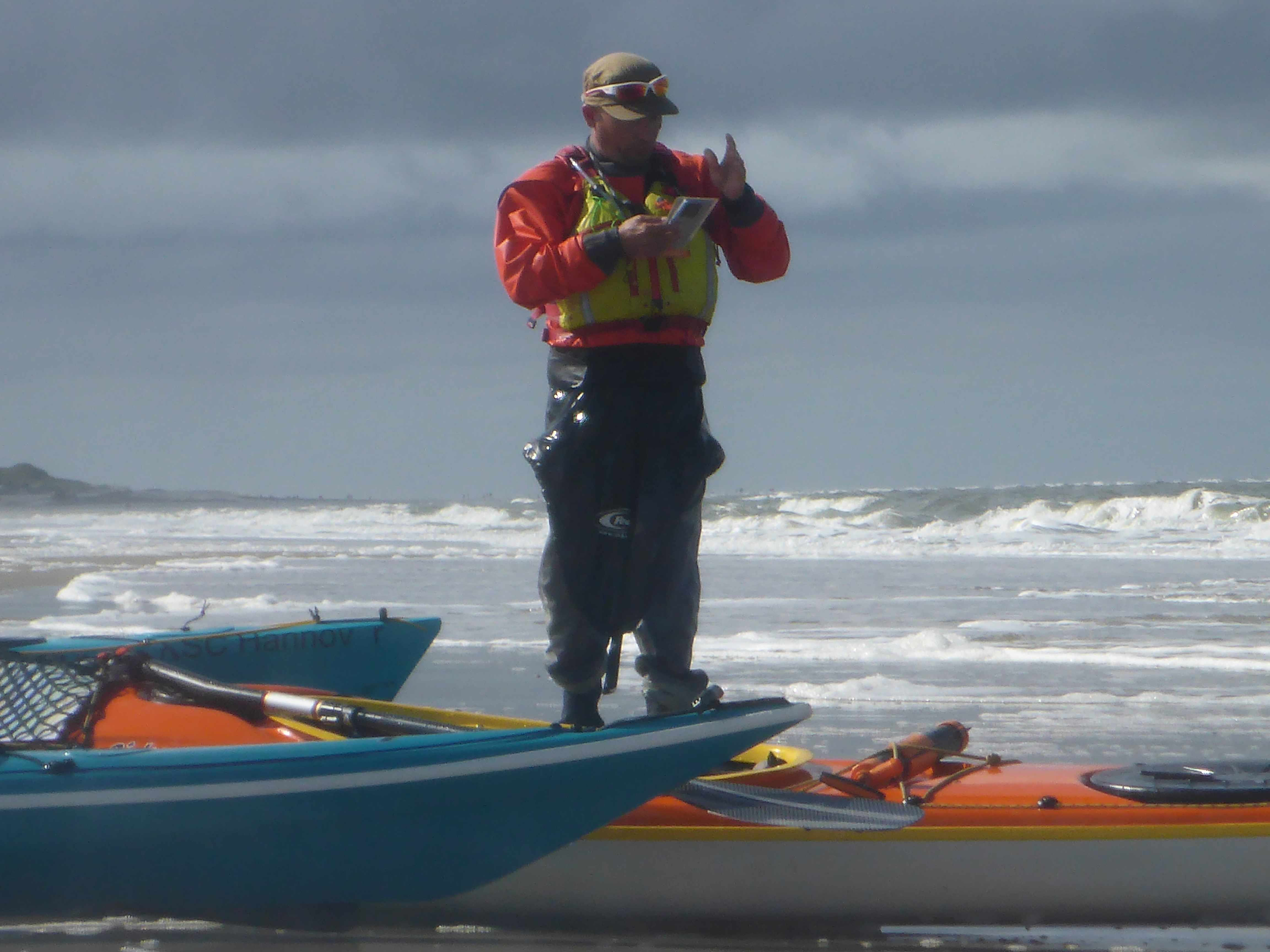 Die Brandung vor Langeoog. Im Vordergrund ein Seekajakfahrer an Land.